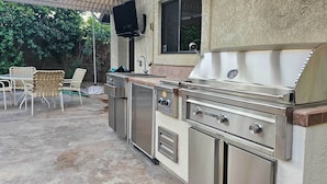 An outdoor kitchen with a grill, sink, and storage cabinets. - Desert Oasis in La Quinta! Heated Pool & Patio (La Quinta)