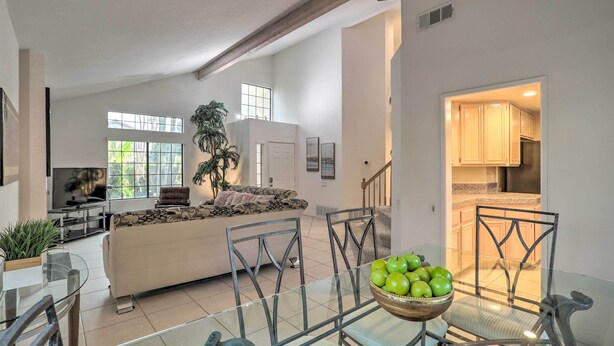 A spacious living area with a glass dining table, a sofa, and a TV. - Desert Oasis in La Quinta! Heated Pool & Patio (La Quinta)