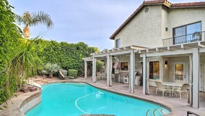 A swimming pool with a stone surround, a covered patio with outdoor furniture, and a house with a balcony. - Desert Oasis in La Quinta! Heated Pool & Patio (La Quinta)