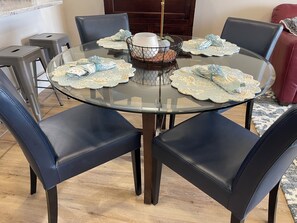 A round glass table with a metal basket centerpiece, surrounded by dark leather chairs. - Boutique condo with beautiful bay views, short walk to the beach. (Fort Myers Beach)
