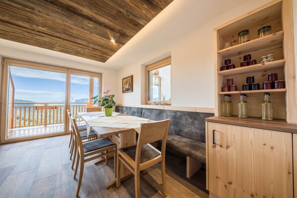A modern kitchen with wooden cabinetry, a dining table, and a view of the outdoors.