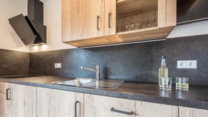 A modern kitchen with wooden cabinets, a stainless steel sink, and a built-in range hood. - Holiday Apartment "Lavendel" with Mountain View, Wi-Fi, Balcony & Sauna (Vöran)