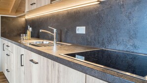Una cocina moderna con un lavamanos de acero inoxidable, un horno empotrado y armarios de madera.