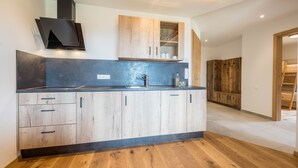 Eine moderne Küche mit Holzausstattung, einer schwarzen Arbeitsplatte und einem eingebauten Herd.