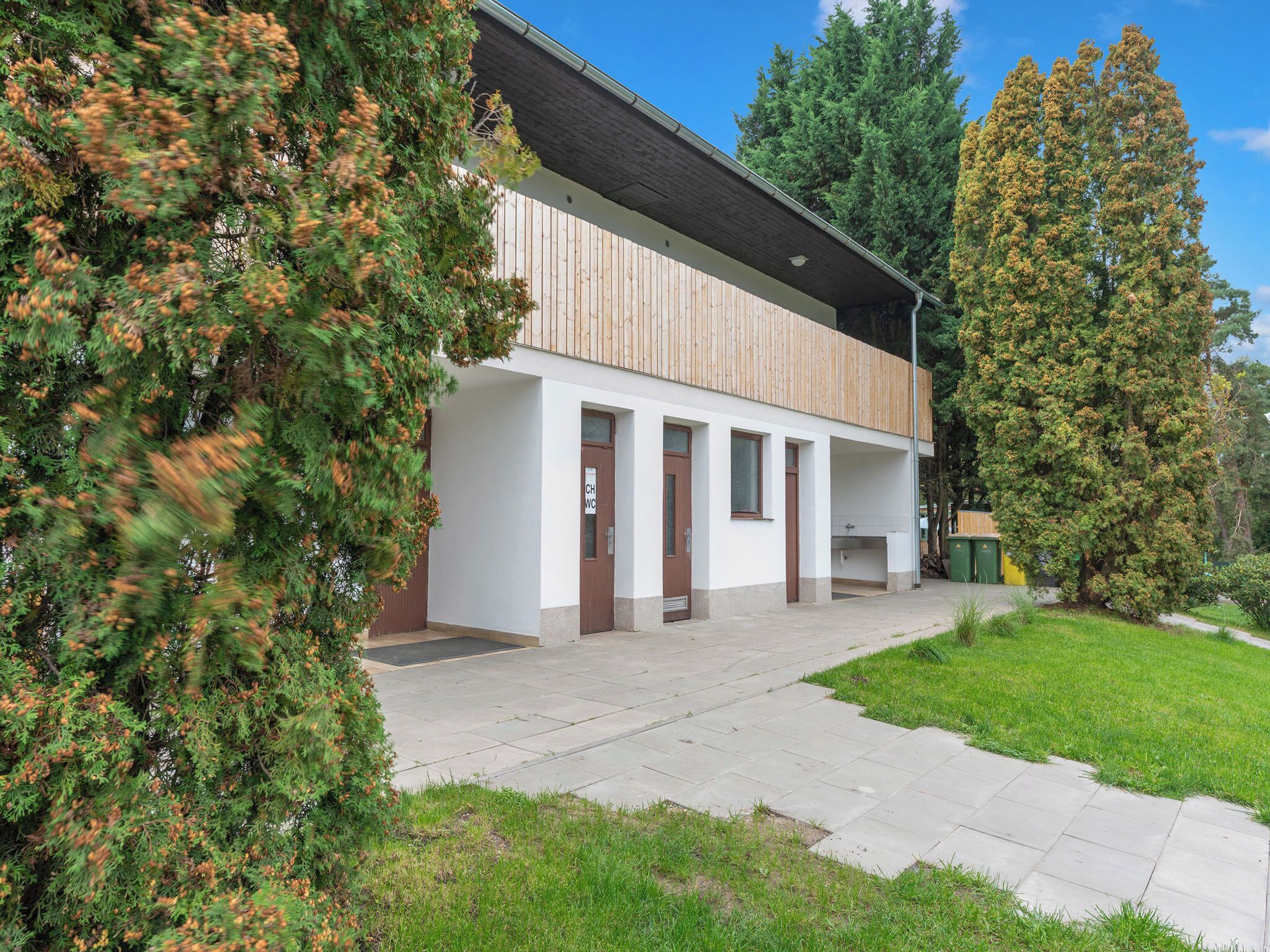 Un bâtiment moderne doté d’une façade en bois, de plusieurs portes et d’une allée couverte.