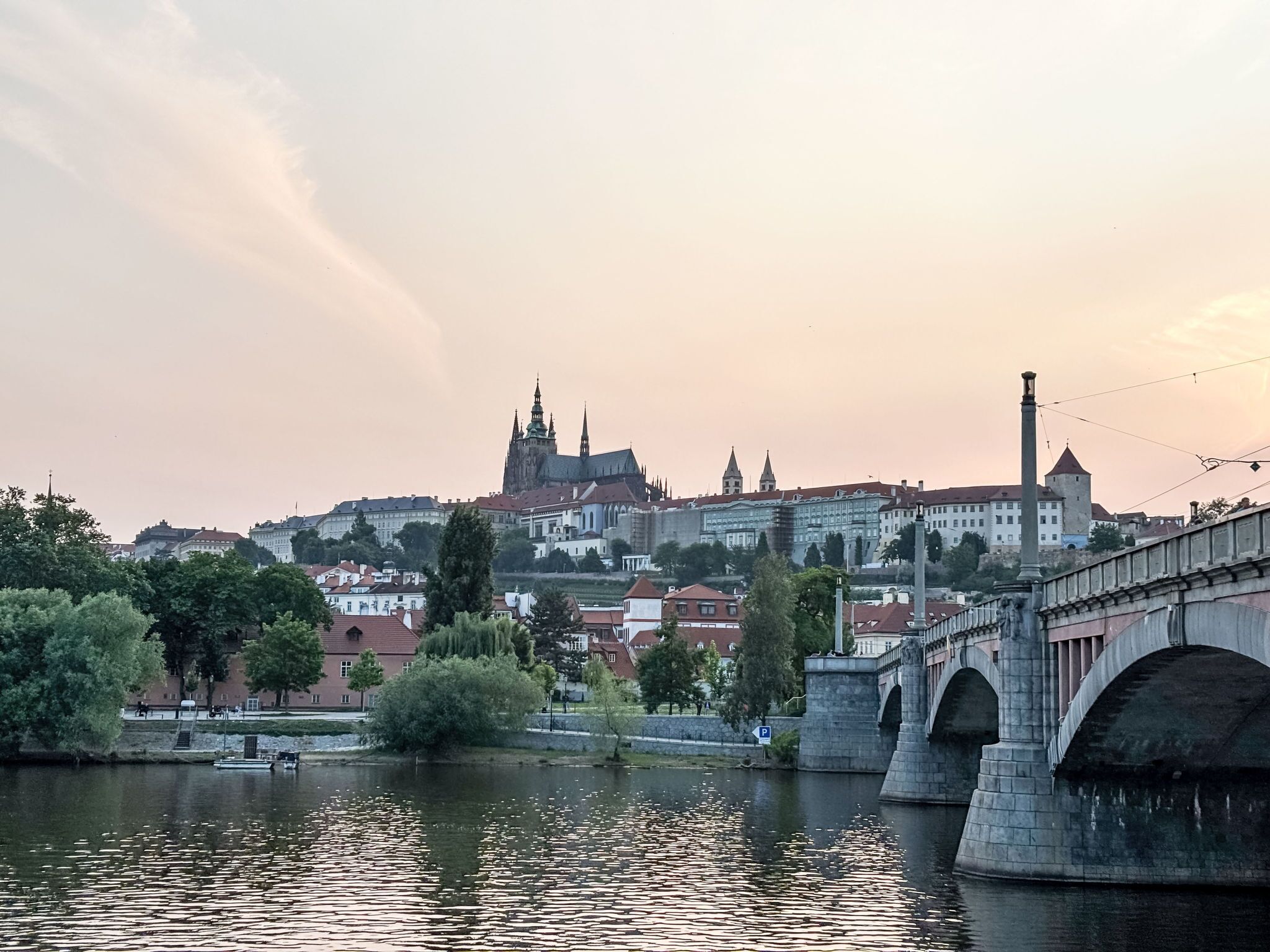 Un pont historique enjambant une rivière, avec une vue sur la ville en arrière-plan, notamment une imposante cathédrale.