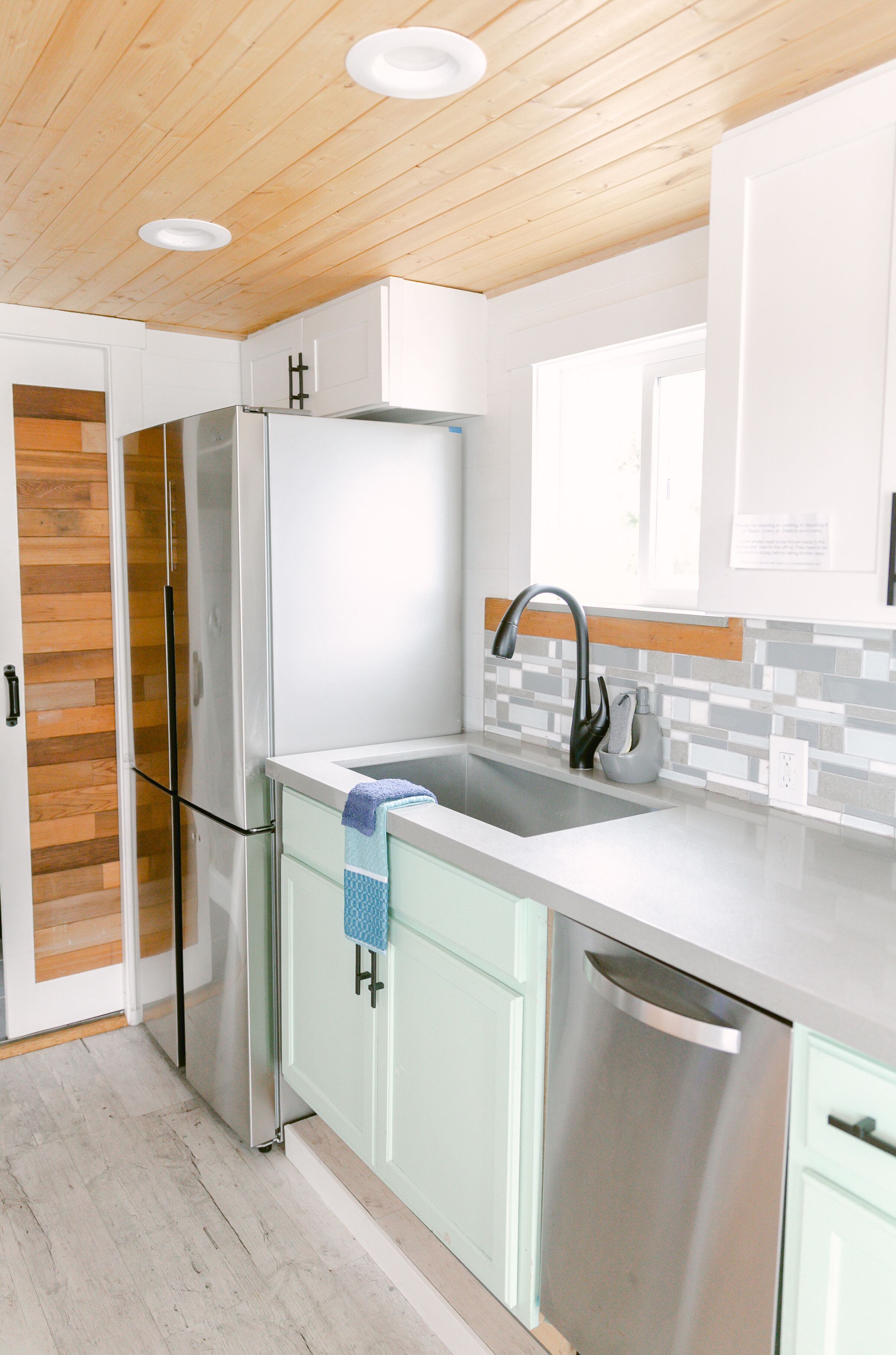 A modern kitchen with a stainless steel refrigerator, a dishwasher, and a sink with a faucet.