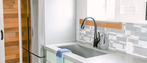 A modern kitchen with a stainless steel refrigerator, a dishwasher, and a sink with a faucet.
