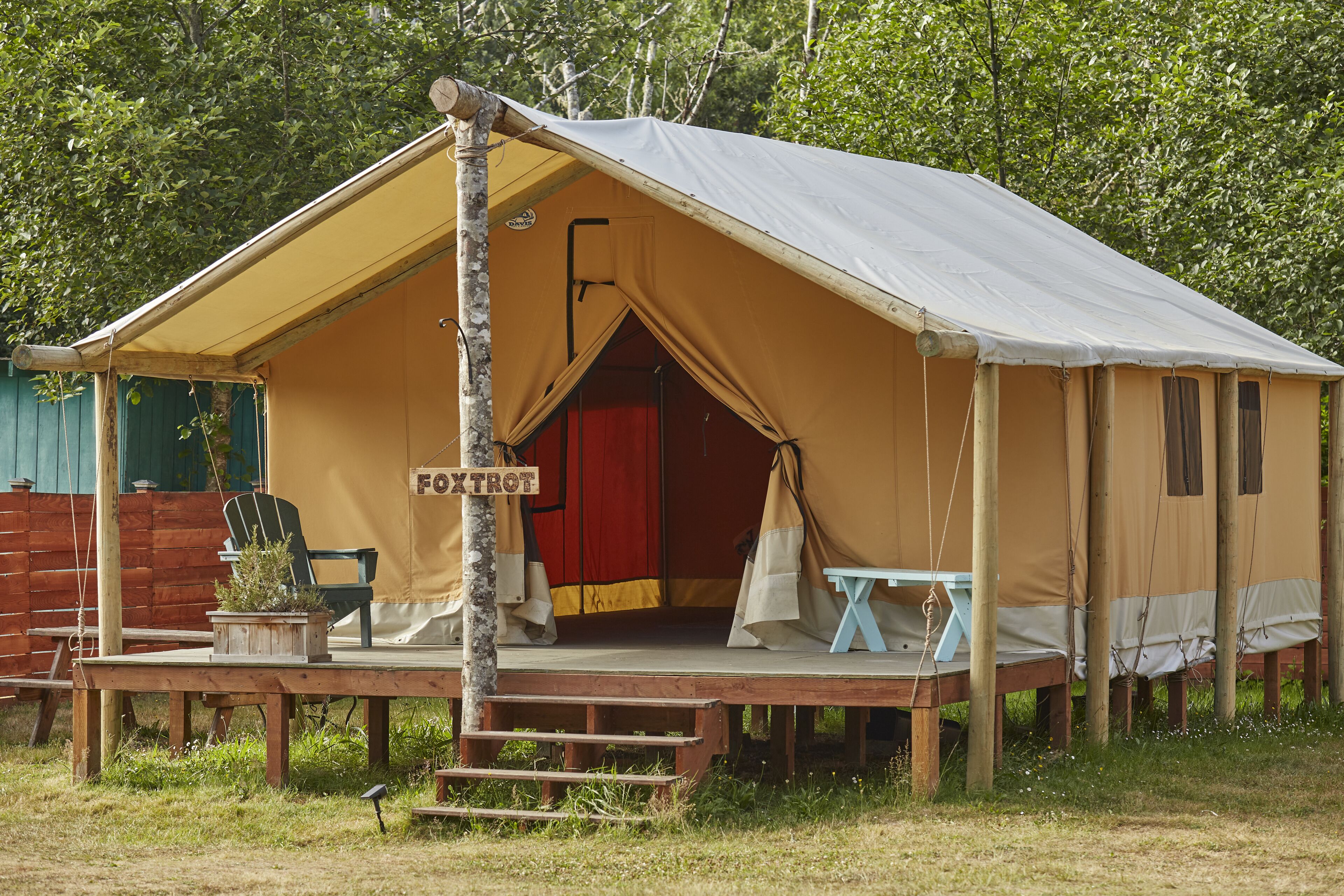 A tent with a porch, a chair, and a table.