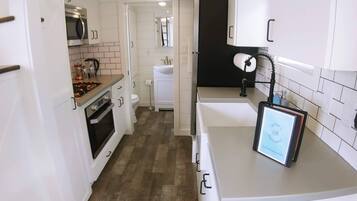 A compact kitchen with white cabinets, a microwave, a stove, and a sink.
