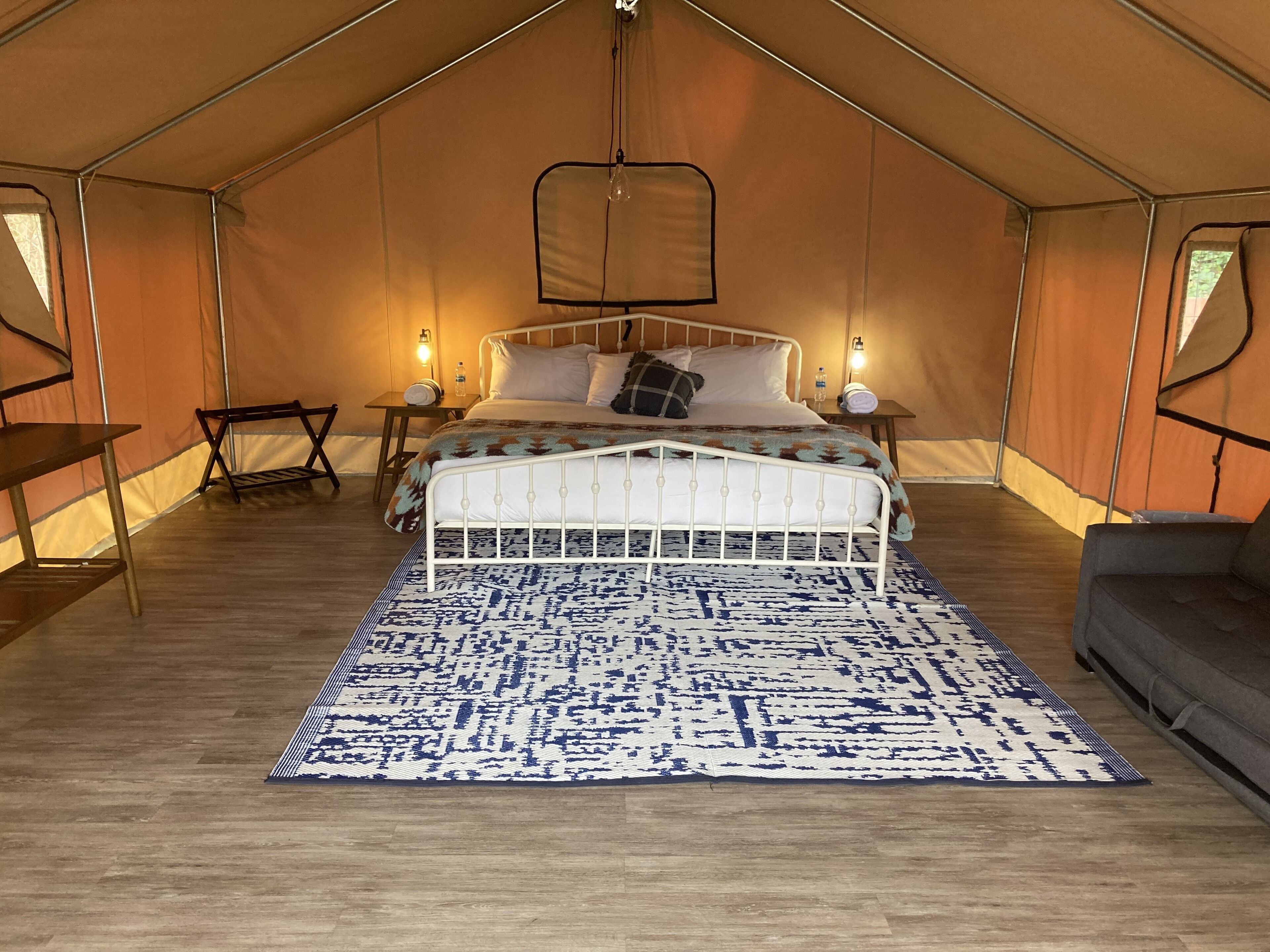 A tented room with a bed, bedside tables, and a hanging light fixture.