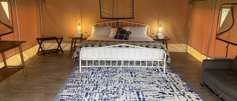 A tented room with a bed, bedside tables, and a hanging light fixture.