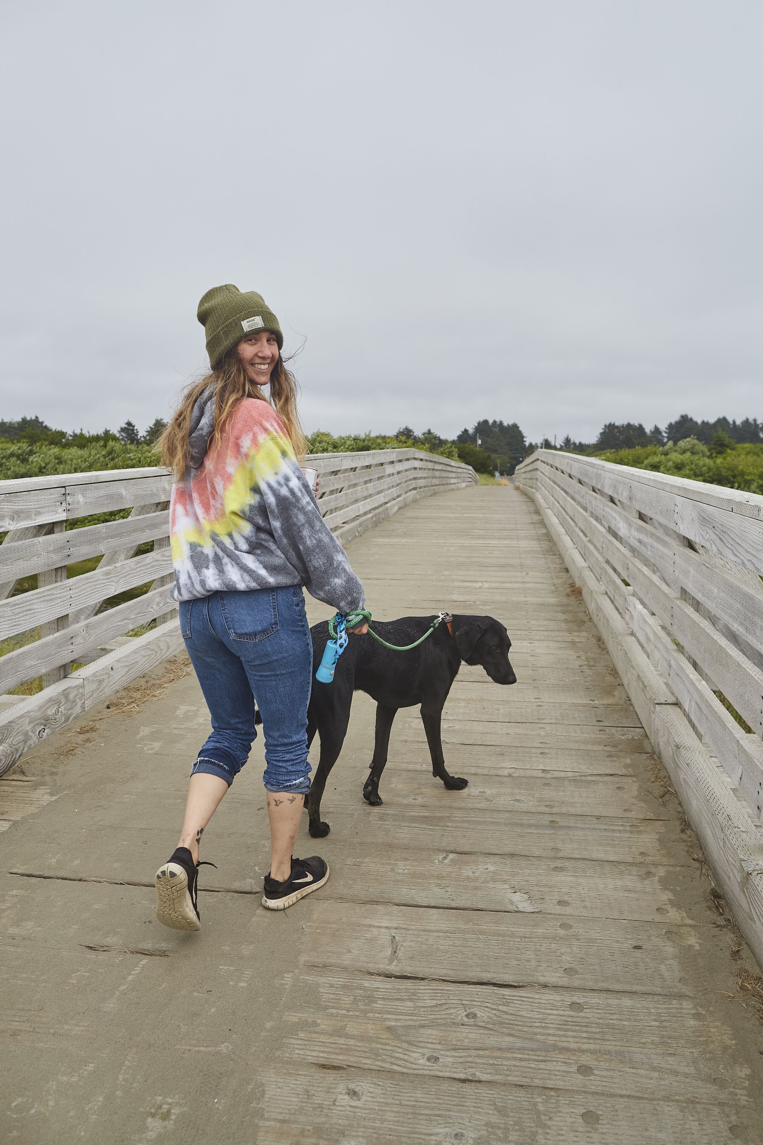 Una persona pasea un perro sobre un puente de madera con barandillas.
