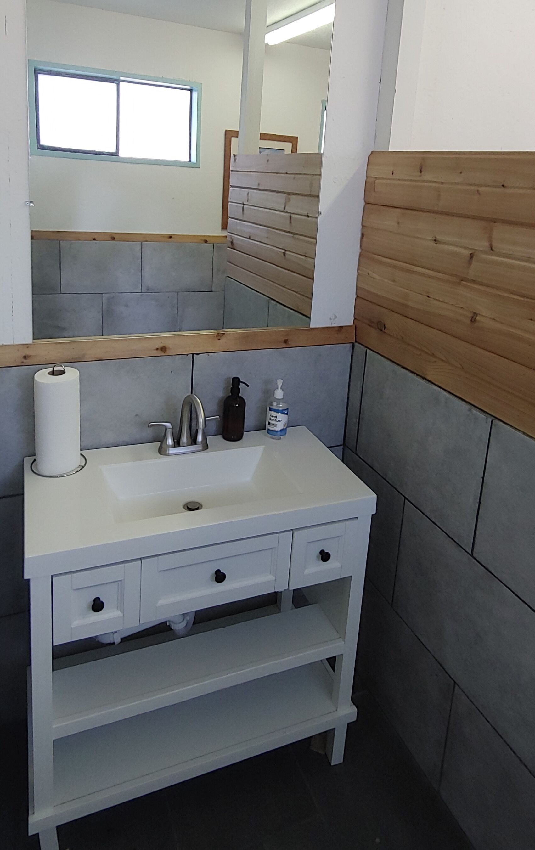 A bathroom with a white sink, wooden paneling, and a mirror.
