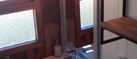 A bathroom with a white sink, a mirror, and a shelf above the sink.