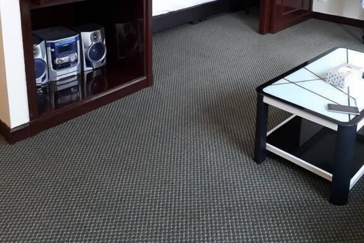 A hotel room with a bed, a television, a coffee table, and a bookshelf.