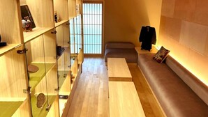 Ein Hotelzimmer mit Holzboden, einer Couch, einem Glastisch und Blick durch ein Fenster mit Gittermuster.