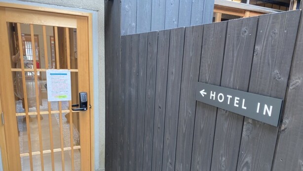 Ein hölzernes Tor mit einem Schild, das den Weg zum Hotel weist.