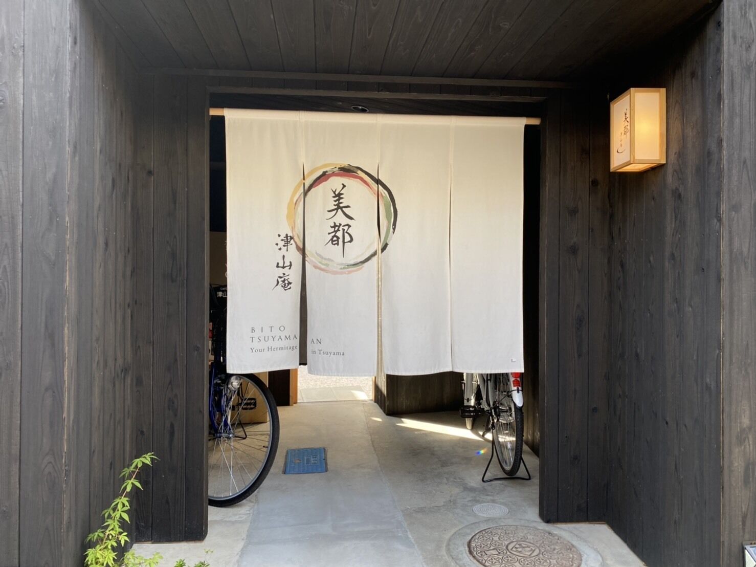 A wooden entrance with a bicycle parked to the side and a sign with Japanese characters.