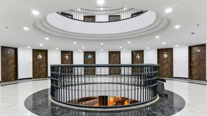 A spacious lobby with a central circular area, multiple wooden doors, and a modern railing. - Aura Apartment Da Lat (Xuan Huong - Da Lat)