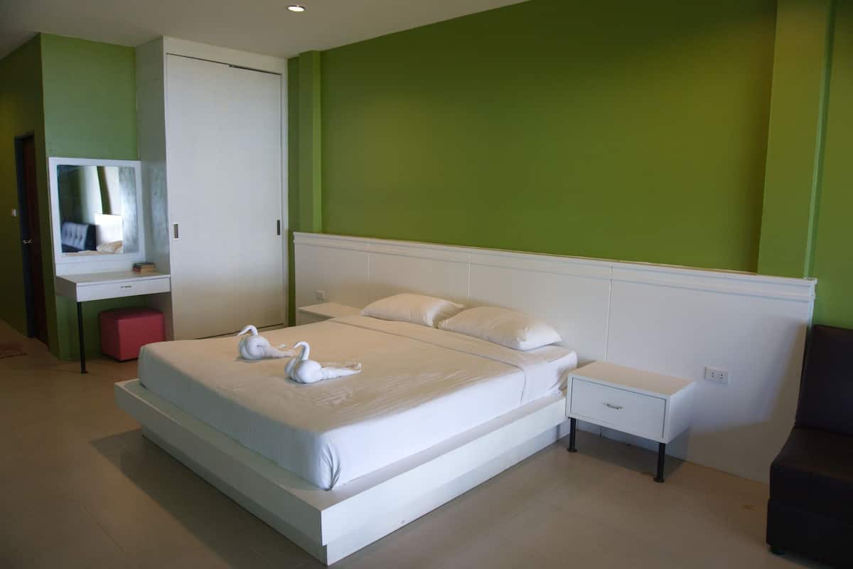 Un dormitorio moderno con una cama grande, una mesita de noche, un tocador y un espejo.