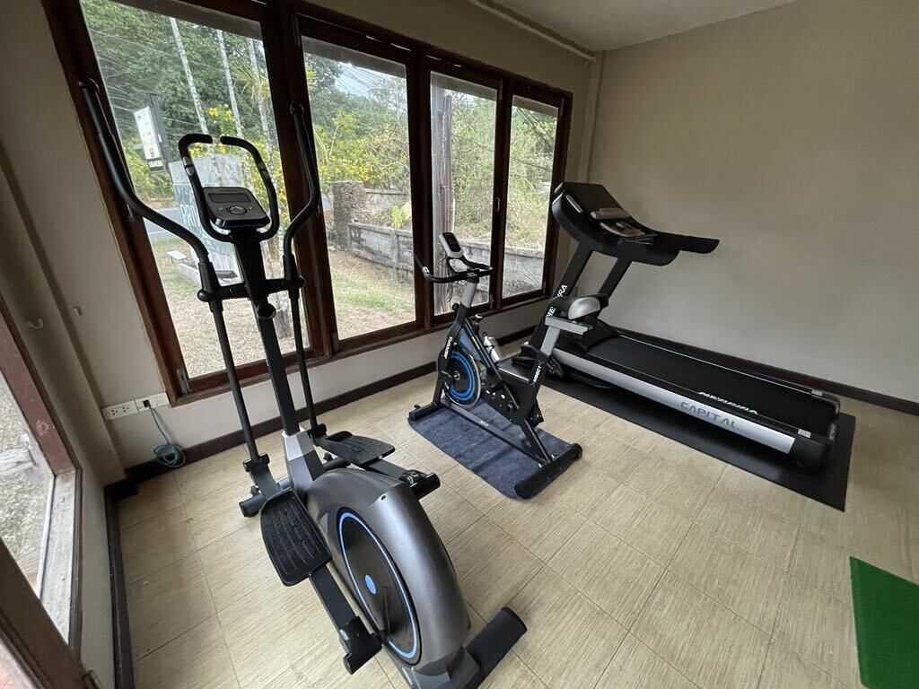 Un gimnasio con equipo de cardio, incluyendo una elíptica, una bicicleta estática y una cinta de correr.