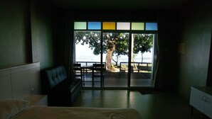 A hotel room with a bed, a bench, and a view of the beach through a large window. - Koh Chang Privilege (Ko Chang)