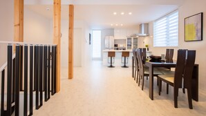 Una cocina moderna con armarios blancos, una isla central y taburetes de bar.