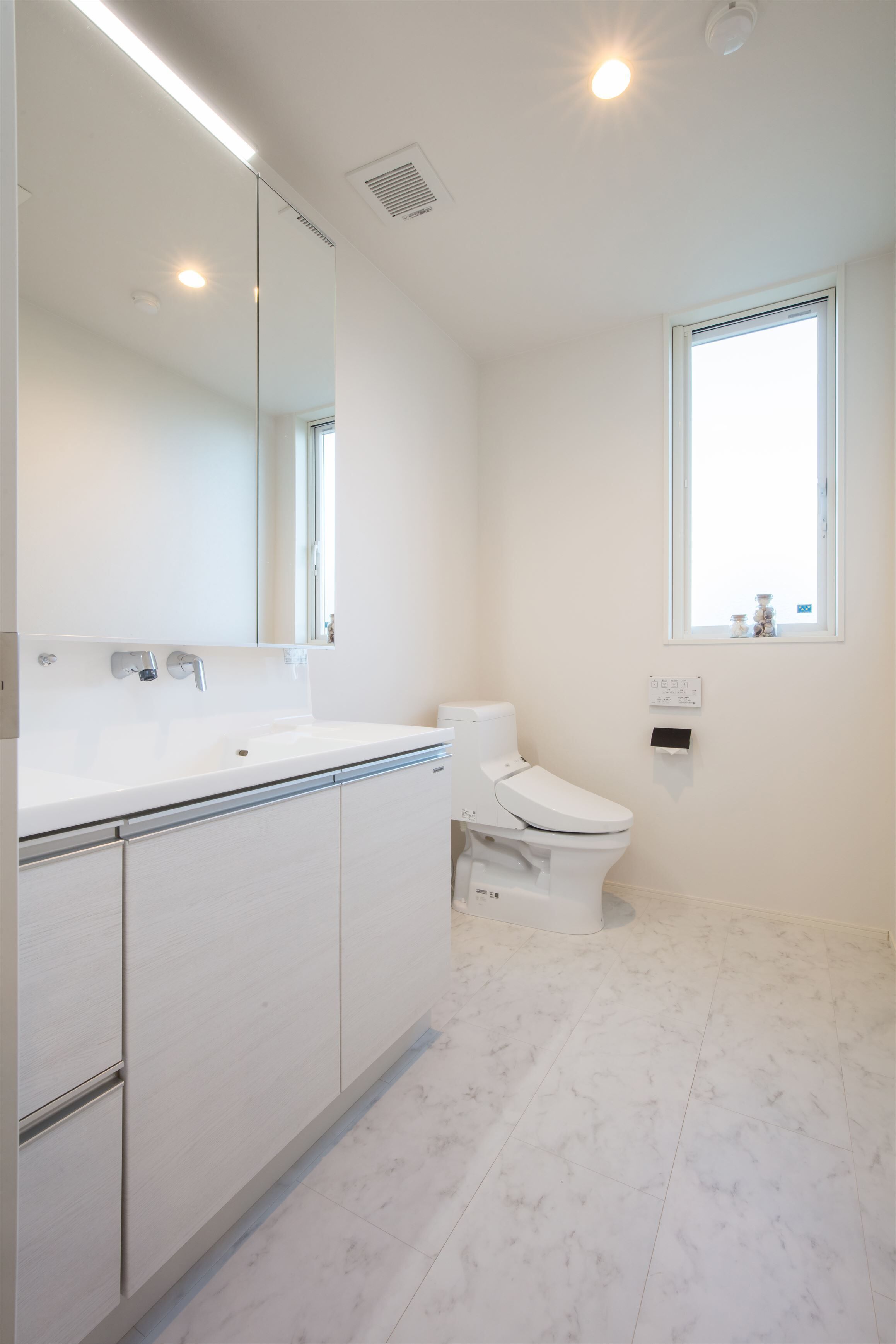 A modern bathroom with a white sink, mirror, and toilet.