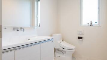 A modern bathroom with a white sink, mirror, and toilet.