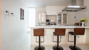 Una cocina moderna con una isla central, taburetes de bar, una campana extractora de acero inoxidable y un horno empotrado.