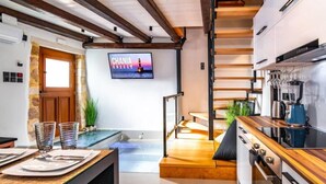 Een moderne keuken met een houten plafond, een aan de muur bevestigde televisie en een keukeneiland met zitplaatsen.