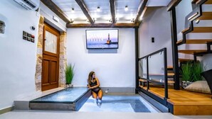 Een modern interieur met een zwembad, een houten deur en een televisie waarop 'CHANIA GREECE' staat.