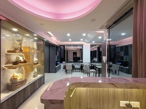 A modern interior with a curved marble counter, glass display cases, and a central seating area with tables and chairs. - Hands B&B (Magong)