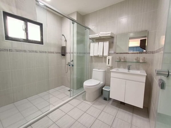 A modern bathroom with a glass shower enclosure, a toilet, a sink, and a mirror above the sink. - Hands B&B (Magong)
