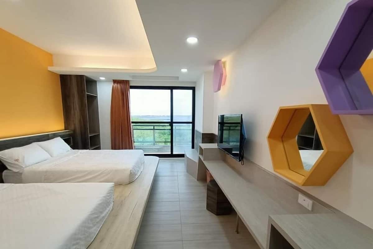 A hotel room with two beds, a TV, a large window, and a unique hexagonal shelf.