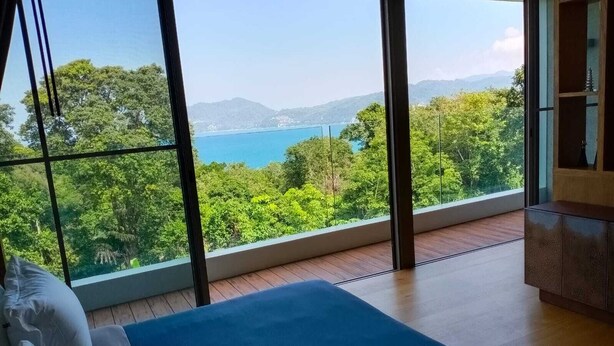Camera da letto con un'ampia finestra che si affaccia su una foresta e un lago.