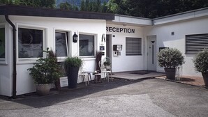 A reception area with a sign, a small seating area, and potted plants. - Inter-Alp (Saint-Maurice)