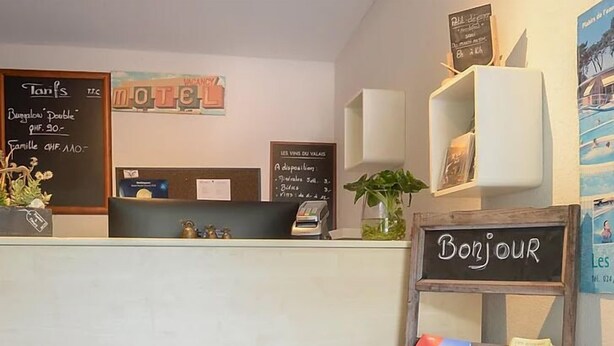 A reception desk with a 'Bonjour' sign, a bulletin board with a 'Vacancy' sign, and a small plant. - Inter-Alp (Saint-Maurice)