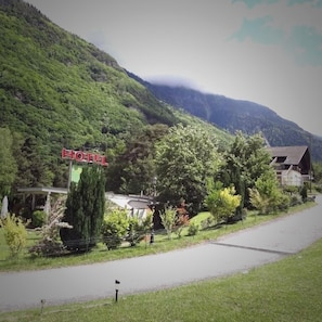 A hotel with a sign, surrounded by lush greenery and a mountain backdrop. - Inter-Alp (Saint-Maurice)
