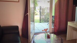 A room with a glass table, a sofa, a sliding glass door leading to a patio, and a framed picture on the wall. - Inter-Alp (Saint-Maurice)