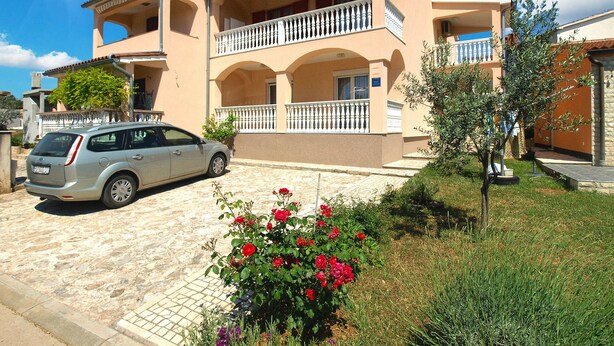 A two-story building with a balcony, a car parked in front, and a garden with flowers. - Apartment 934/2231 (Istria - Fažana), 500m from the beach (Fažana)