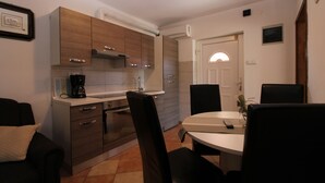 A compact kitchen with modern appliances, a dining area with a round table and chairs, and a door leading to another room. - Apartment 934/2231 (Istria - Fažana), 500m from the beach (Fažana)