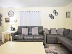 Uma sala de estar com sofá, mesa de centro e mesa lateral com luminária.