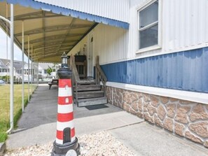 Ein Gebäude mit einer überdachten Veranda, einem Leuchtturm-artigen Pfeiler und einer Treppe, die zu einer Tür führt.