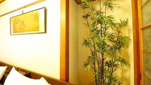 A traditional Japanese room with a bamboo plant, a framed artwork on the wall, and wooden paneling. - Dai3Himawari  401 (Hiroshima)