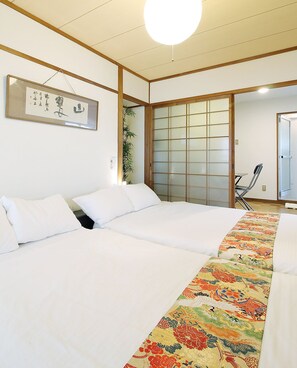 A traditional Japanese-style room with tatami flooring, a shoji screen door, and a bed with a colorful embroidered bedspread. - Dai3Himawari Building 501 (Hiroshima)