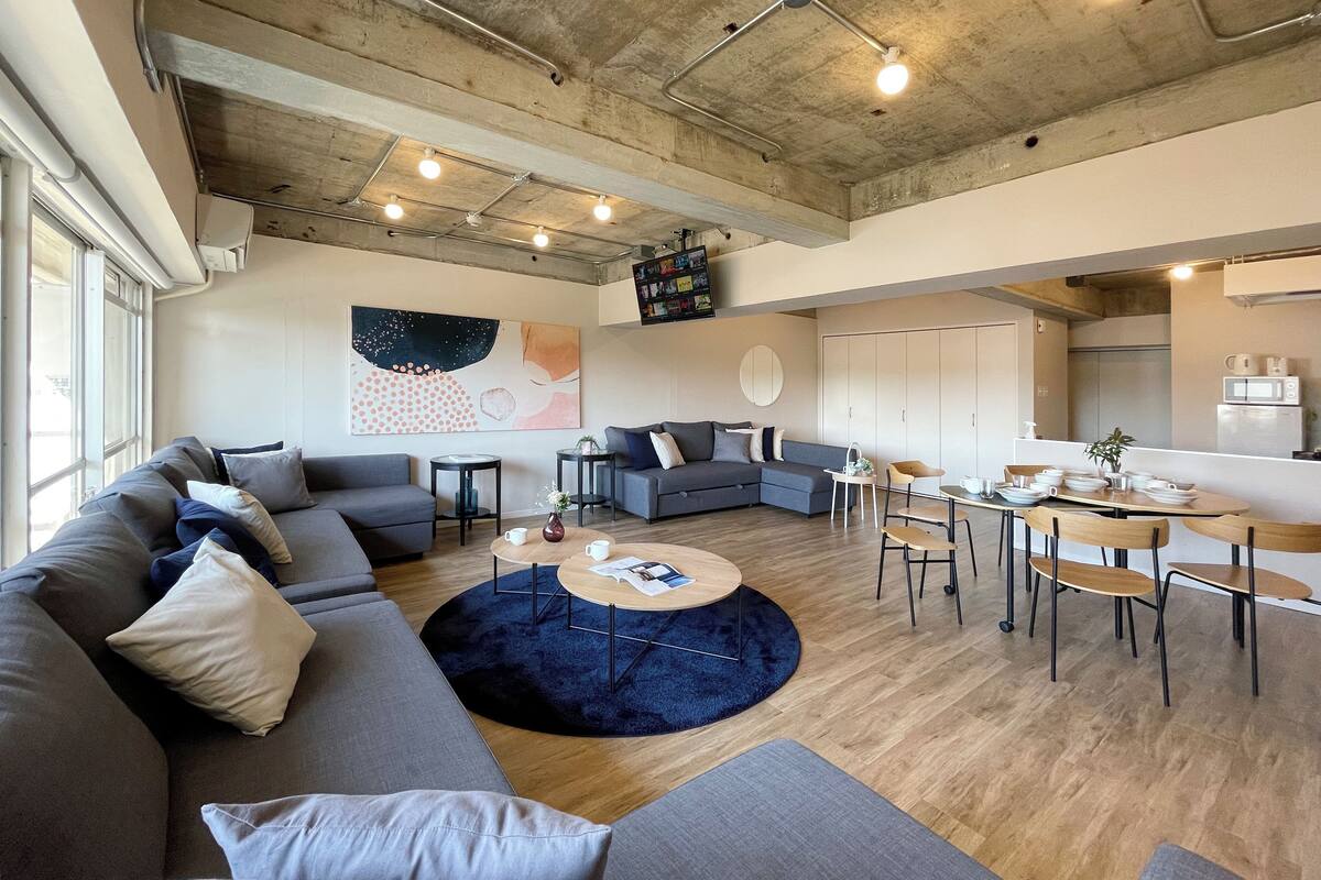 A modern living room with a sectional sofa, a round coffee table, and a dining area with a table and chairs.