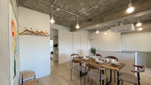 A modern dining area with a long wooden table, six chairs, and hanging lights.