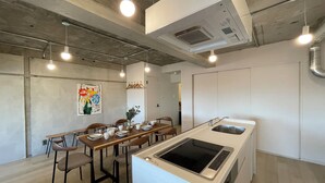 A modern kitchen with a central island, dining area with chairs, and pendant lighting.